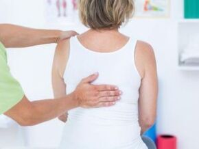 Een patiënt met klachten van rugpijn in het gebied van de schouderbladen wordt door een arts onderzocht